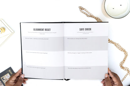 Open book of the I AM SAFE Journal with 'Alignment Reset' and 'Safe Check' sections on a white surface with a candle and chain.